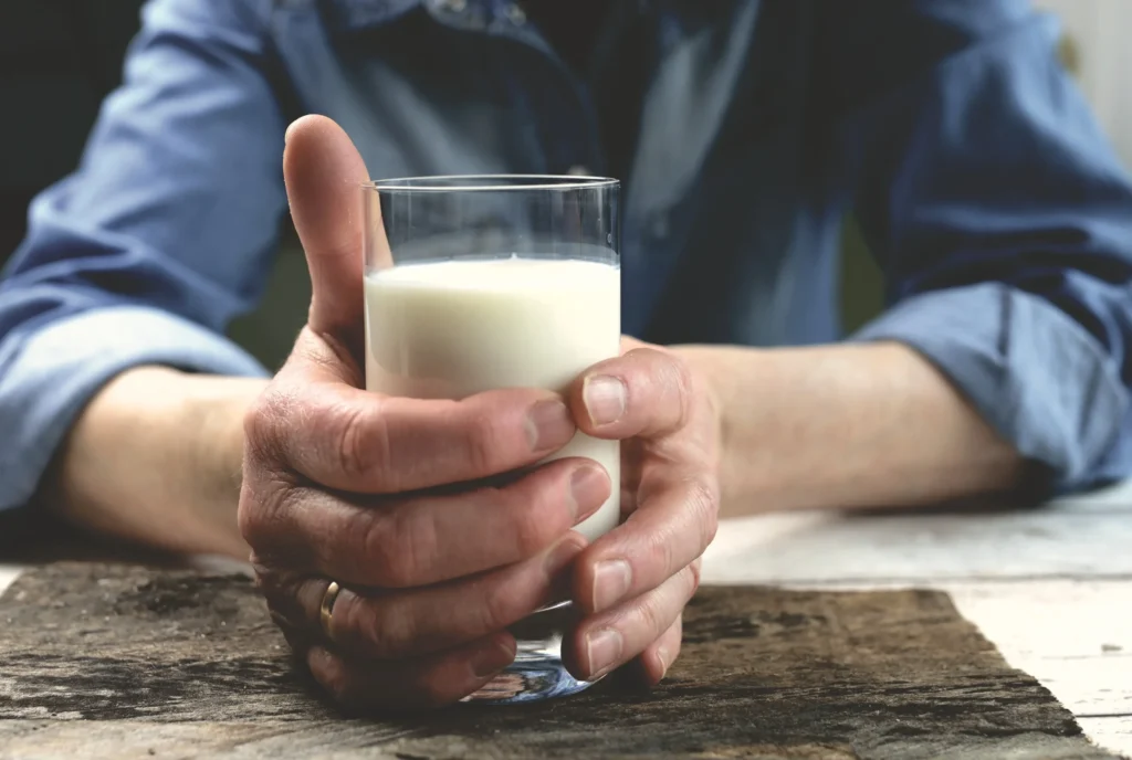 Une personne tient un verre de lait.