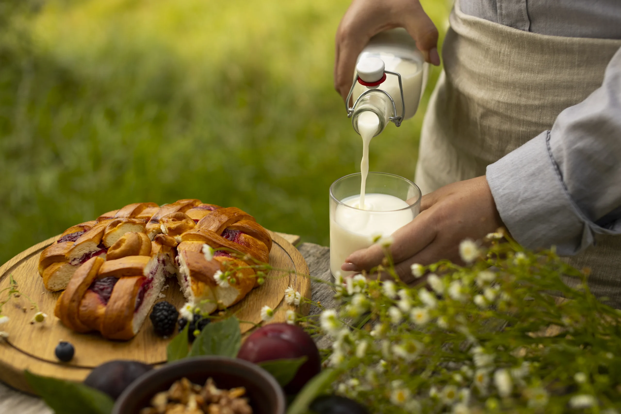 Un gâteau basque et une personne avec un tablier qui verse du lait dans un verre.